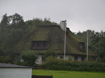 Reetdachhaus mit zwei Fahnenmästen davor