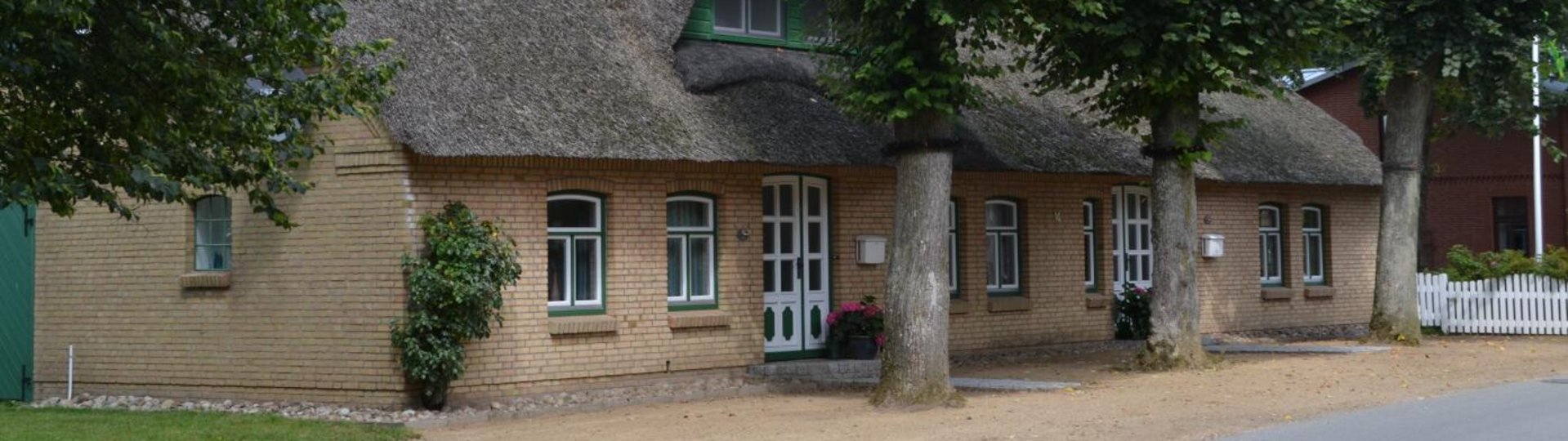 Reetdachhaus mit grünen Fensterrahmen