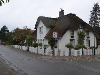 weißes Reetdachhaus mit weißem Zaun